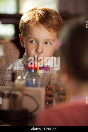 Piccolo ragazzo beve con un tubulo Foto Stock