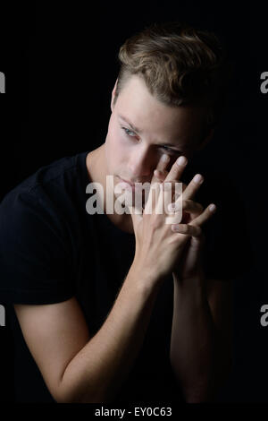 Un uomo triste guardando lontano. Un buio ritratto emotivo. Foto Stock