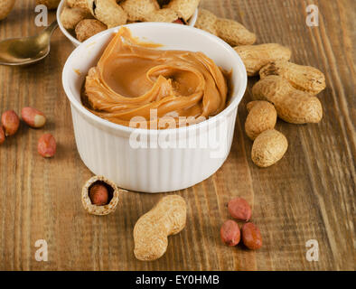 Burro di arachidi in una ciotola bianca con arachidi. Dof poco profondo. Foto Stock