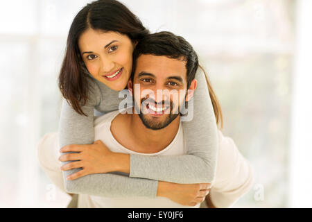 Felice giovani indiani giovane divertendosi con piggyback per interni Foto Stock