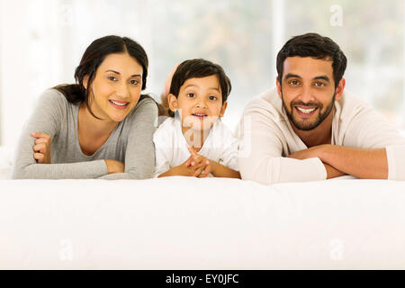 Ritratto di giovane e bella famiglia indiana rilassante sul letto Foto Stock