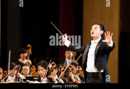 Yuxi, la Cina della provincia dello Yunnan. 18 Luglio, 2015. Conductor Zhang Chengjie è visto durante un concerto a Nie Er teatro in Yuxi, a sud-ovest della Cina di Provincia di Yunnan, luglio 18, 2015. Come parte della settimana musica cinese di memorizzare il celebre compositore Nie Er, l orchestra sinfonica di Shanghai Opera House fornito una prestazione per i residenti locali. © Lyu Shuai/Xinhua/Alamy Live News Foto Stock