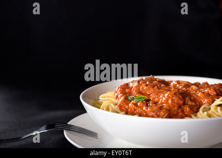 Spaghetti con sugo di tonno su sfondo nero con spazio di copia Foto Stock