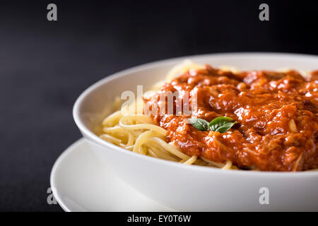 Spaghetti con sugo di tonno su sfondo nero con spazio di copia Foto Stock