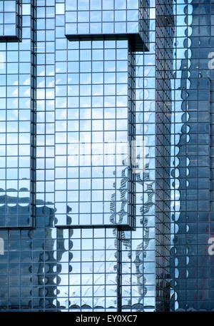 Blu con pareti di vetro di un grattacielo moderno che riflette gli altri edifici, Cielo e nubi bianche. Foto Stock