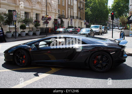 Edgeware Road, Londra, Regno Unito. 19 Luglio, 2015. Il conducente di un 750 hp Lamborghini si impegna in una conversazione di testo mentre in carica della sua 217mph hypercar a Londra, Edgeware Road, apparentemente inconsapevole dei pericoli di non concentrare correttamente mentre in chage di un tale immesely pwerful il veicolo in una zona trafficata. Credito: Paolo Davey/Alamy Live News Foto Stock