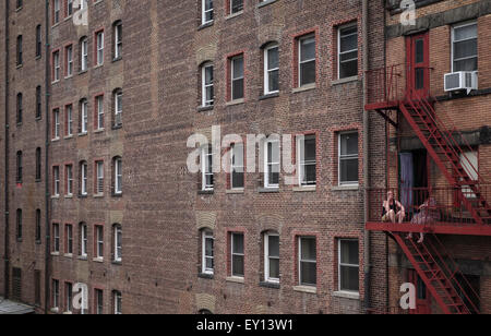 Due donne al di fuori seduta sulla via di fuga in caso di incendi, fumatori, edificio accanto alla linea alta, New York City, Manhattan STATI UNITI D'AMERICA. Foto Stock