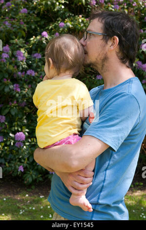 Baby girl essendo confortato da suo padre in giardino Foto Stock