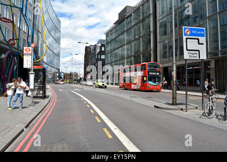 Una coppia si trova a una fermata dell'autobus a Bishopsgate, Norton Folgate, Londra, Inghilterra, Regno Unito Foto Stock