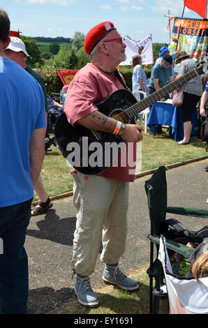 Tolpuddle, Dorset, Regno Unito. 19 Luglio, 2015. Una unione dedicato l uomo ascolta uno degli altoparlanti, completa con la chitarra a Tolpuddle, Dorset, Regno Unito domenica 19 luglio 2015. Ogni mese di luglio il villaggio di Tolpuddle nel Dorset, Regno Unito, tenere questo festival in memoria dei martiri Tolpuddle. I martiri sono stati sei i lavoratori agricoli che hanno vissuto e lavorato nel villaggio di Tolpuddle. Essi sono stati arrestati il 24 febbraio 1834 sulla carica di fare un giuramento illegale. L'effettivo reato è stato nel formare un sindacato per affrontare le loro condizioni di lavoro insoddisfacenti. Credito: Grahame Howard/Alamy Live News Foto Stock