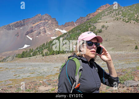 Una femmina di un escursionista nel deserto per parlare a qualcuno sul suo telefono cellulare. Foto Stock