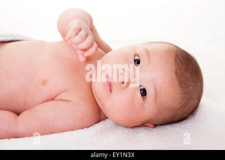 Bambino sdraiato su un lato e guardando la telecamera, Foto Stock