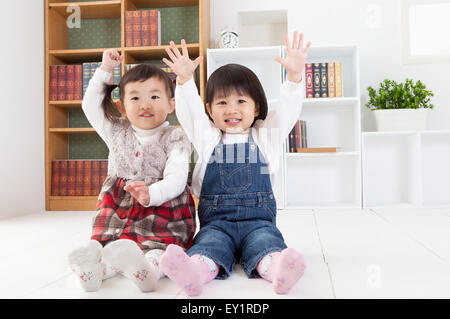 Bambine seduto sul pavimento con le mani insieme, Foto Stock