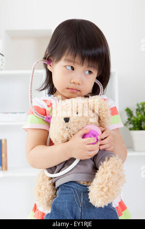 Little Girl holding Teddy bear e guardando lontano, Foto Stock