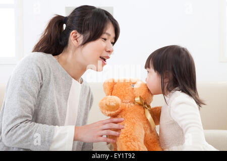 La madre e il bambino girl holding e baciando un orso di peluche Foto Stock