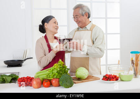 Coppia senior di bere il vino rosso e sorridente felicemente, Foto Stock