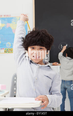 Figli che studiano in aula e sorridente alla telecamera, Foto Stock