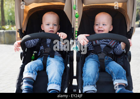 Ritratto di baby fratelli gemelli in passeggini a park Foto Stock