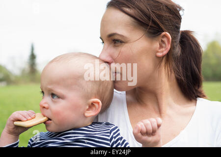 Ritratto di giovane madre kissing baby figlio nel campo Foto Stock