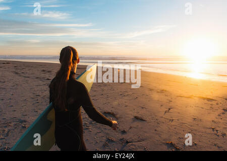Vista posteriore del surfista femmina camminando sulla spiaggia verso il mare, Cardiff-By-The-Sea, CALIFORNIA, STATI UNITI D'AMERICA
