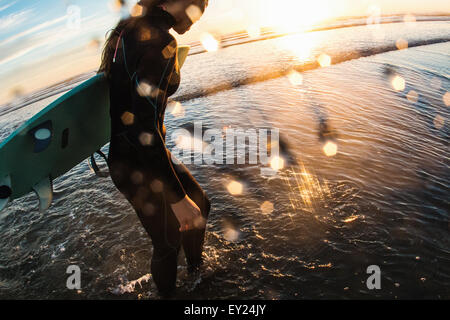 Surfista femmina paddling in mare al tramonto, Cardiff-By-The-Sea, CALIFORNIA, STATI UNITI D'AMERICA Foto Stock