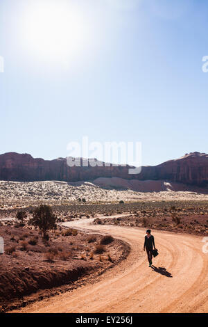 Metà donna adulta a piedi lungo zone rurali su strada sterrata, Monument Valley, Utah, Stati Uniti d'America Foto Stock