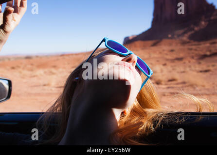 Donna Pendente ritornare al di fuori della finestra di auto, Monument Valley, Utah, Stati Uniti d'America Foto Stock