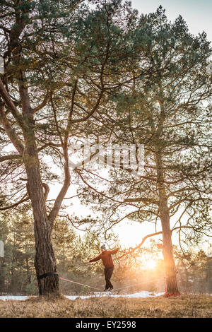 Giovane uomo bilanciamento sulla slackline nella foresta in riva al lago Foto Stock