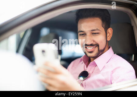 Giovane imprenditore smartphone lettura testo alla finestra auto Foto Stock