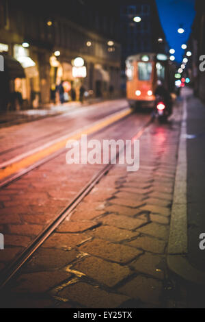 Strada con avvicinamento tram, di notte, Milano, Italia Foto Stock
