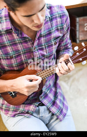 Giovane uomo giocando ukulele, vista in elevazione Foto Stock