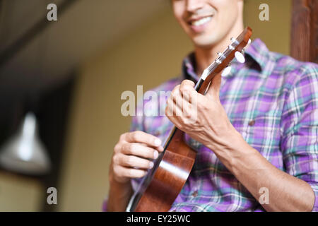 Giovane uomo giocando ukulele Foto Stock