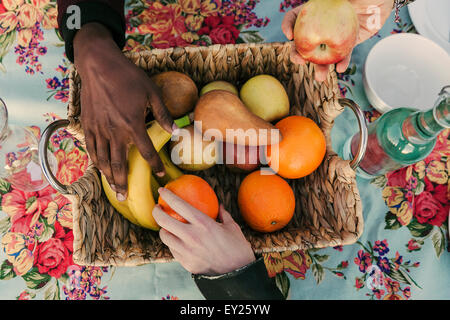 Tre mani di adulti selezione di frutta cesto di forma Foto Stock