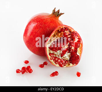 Deliziosa succosa mature melograno e la sua metà con la riflessione su uno sfondo luminoso. Studio shot. Foto Stock