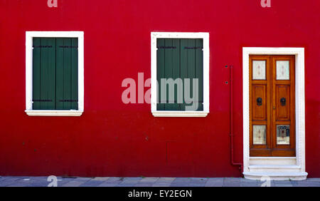 Porta di legno e due finestre sul colore rosso nella parete di Burano Venezia Italia Foto Stock