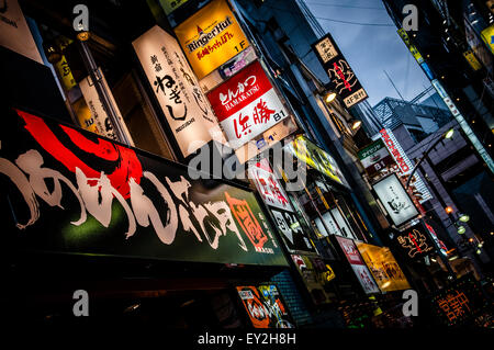 Luci al neon pubblicità aziende come la notte scende nella zona di Shibuya di Tokyo, Giappone Foto Stock