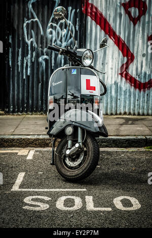 Un scooter Vespa parcheggiata in un motociclo bay con la parola 'solo' segnato sulla strada davanti a esso Foto Stock