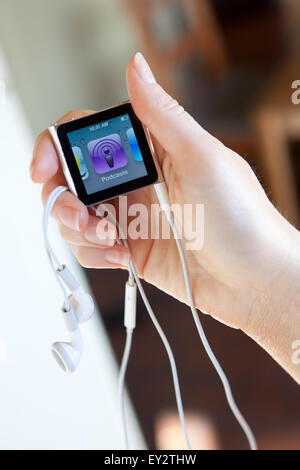 Close up di un Apple iPod nano con cuffie, tenuto in una mano di donna che mostra la schermata di podcast. Foto Stock