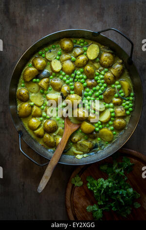 Il segnale di PEA & potatoe curry in una casseruola di ferro sul tavolo di legno. Vista superiore Foto Stock