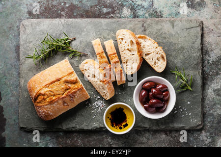 La ciabatta fresco con olio di oliva e di olive su pietra ardesia sfondo Foto Stock