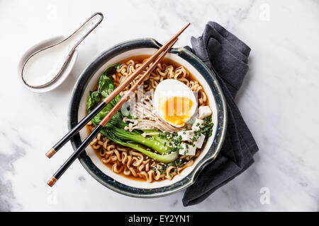 Miso Ramen Asian tagliatelle all'uovo, enoki e pak choi cavolo in ciotola su marmo bianco sullo sfondo Foto Stock