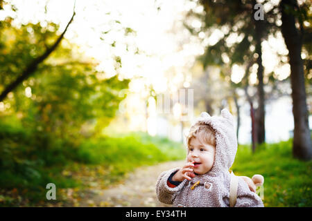 Funny Shy Little 2 anno vecchio ragazzo sogghignando nel parco al tramonto. Infanzia felice concetto. Spazio per il testo. Foto Stock