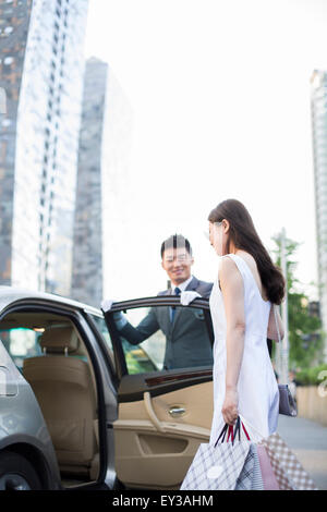 Chauffeur apertura porta auto per una giovane donna Foto Stock