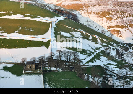 Neve in campi sotto Kinder Scout nei pressi di Hayfield nel Derbyshire. Il paesaggio immerso nella splendida luce della sera. Foto Stock