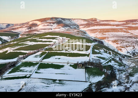 Neve in campi sotto Kinder Scout nei pressi di Hayfield nel Derbyshire. Il paesaggio immerso nella splendida luce della sera. Foto Stock