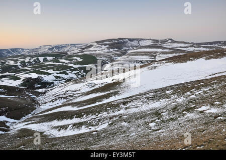 Scampoli di neve sulle colline intorno a Kinder Scout nei pressi di Hayfield nel Derbyshire. Bella luce del tramonto sul paesaggio. Foto Stock