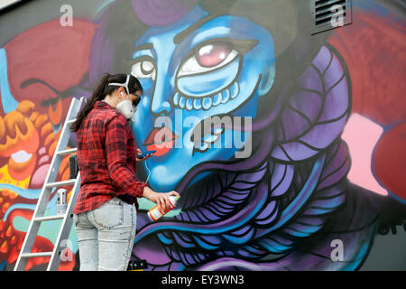 Giovane artista di graffiti murali di spruzzatura in Soho - London REGNO UNITO Foto Stock