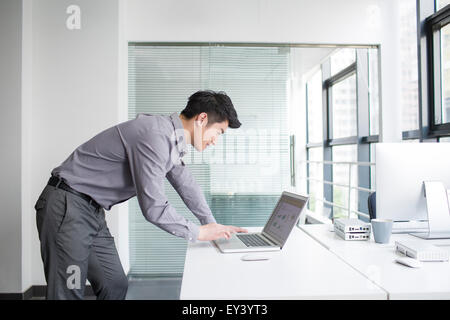 Giovane uomo d affari con computer portatile in ufficio Foto Stock