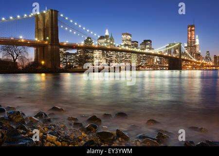 Vista notturna verso Manhattan da Brooklyn con il ponte di Brooklyn Bridge spanning l'East River. Foto Stock