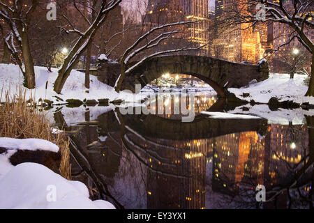 Visualizzare attraverso lo stagno verso Gapstow Bridge in Central Park a Manhattan dopo una tempesta di neve al crepuscolo. Foto Stock